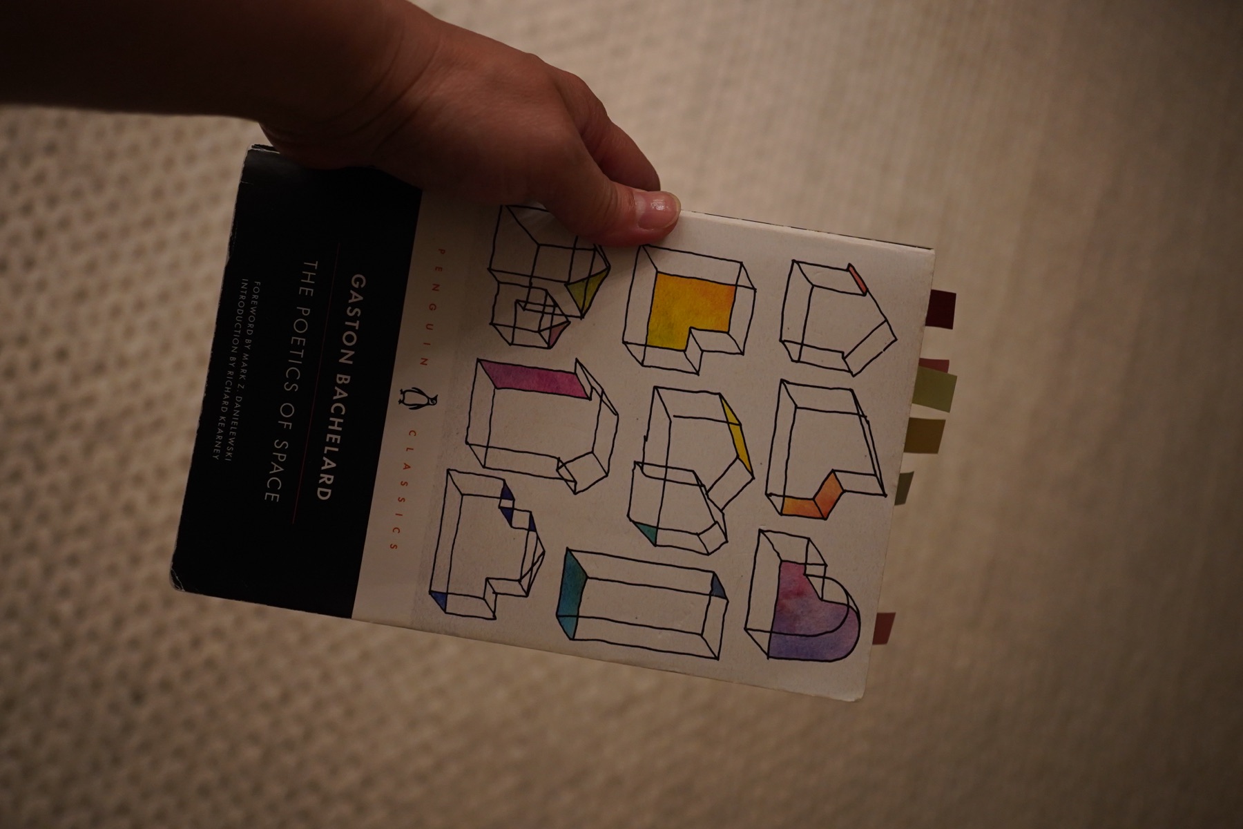 A hand holding a sheet of drawn houses, some filled with colour.